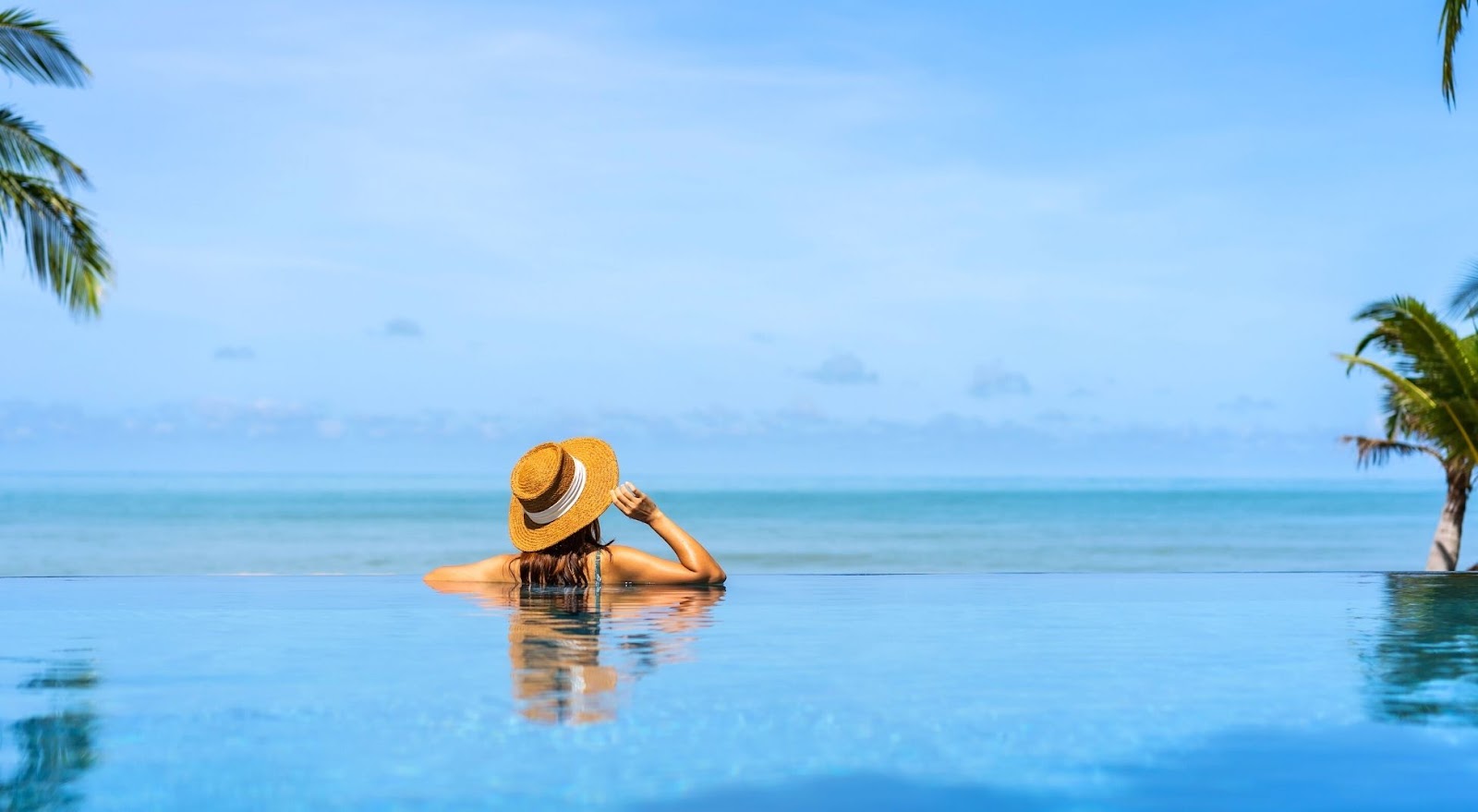 Mulher relaxando em uma piscina com uma vista linda do mar.