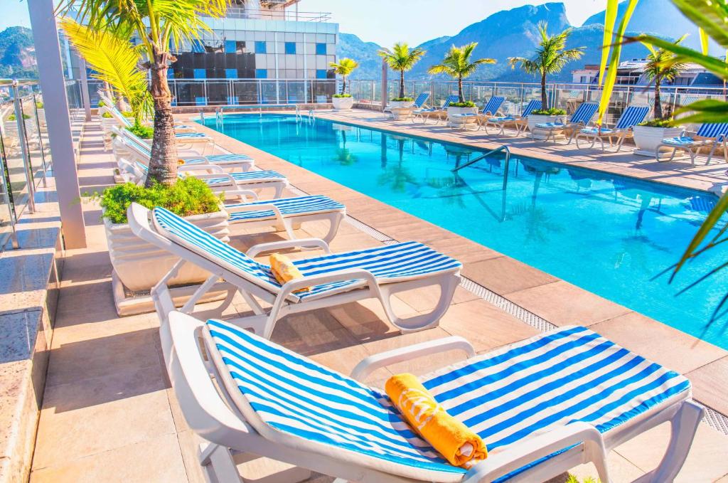 Foto da cobertura de um hotel da Rede Windsor na Barra da Tijuca. Na foto, uma piscina e espreguiçadeiras na beira da piscina.