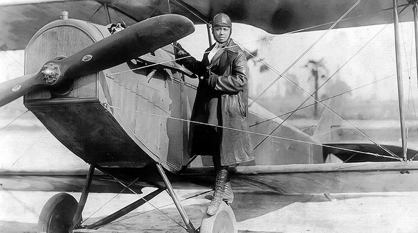 foto preto e branco de uma mulher ao lado de uma aeronave pronta para pilotar