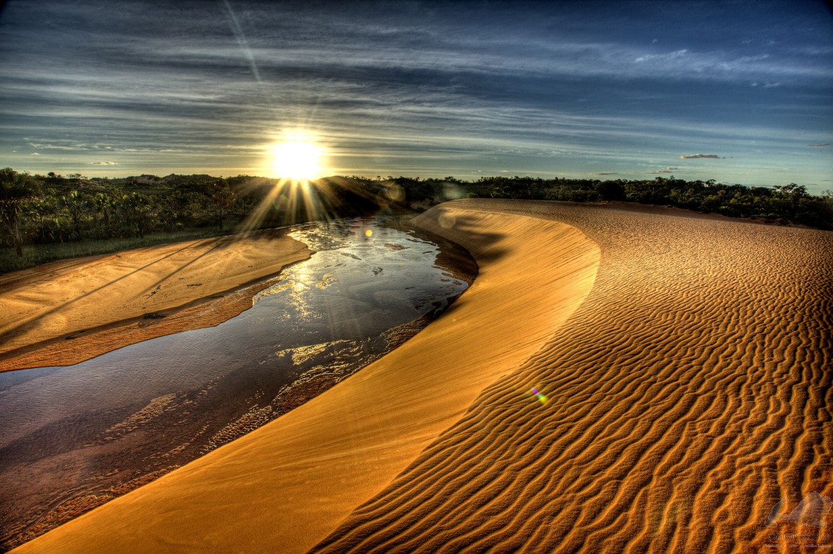 Pôr do sol sobre as dunas douradas do Jalapão com um rio sinuoso ao lado