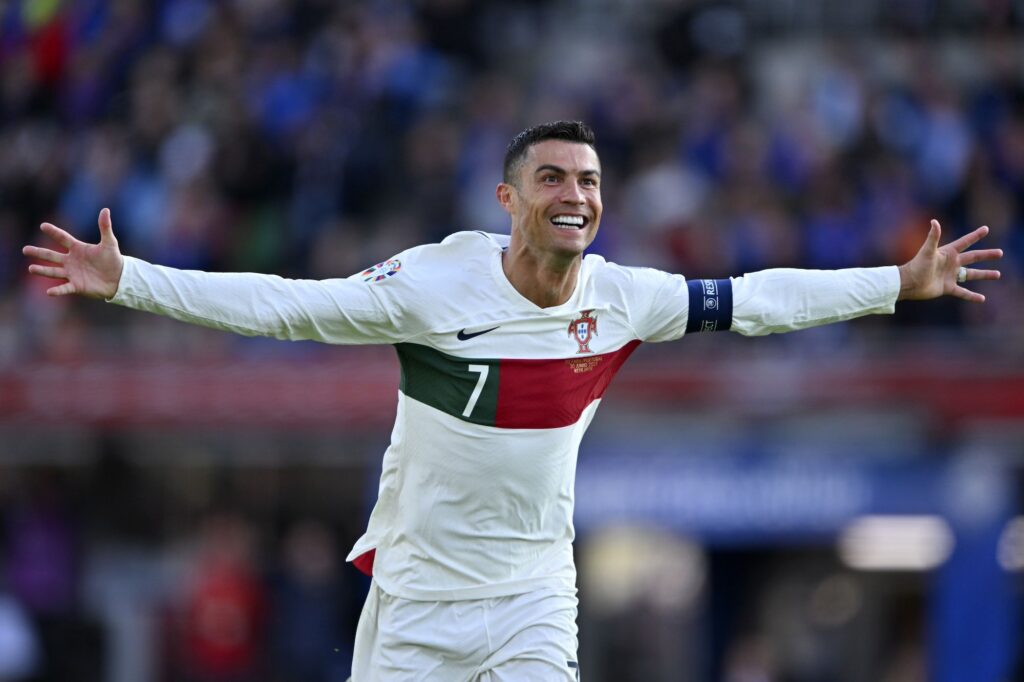 Cristiano Ronaldo comemorando um gol com os braços abertos, vestindo a camisa da seleção portuguesa.