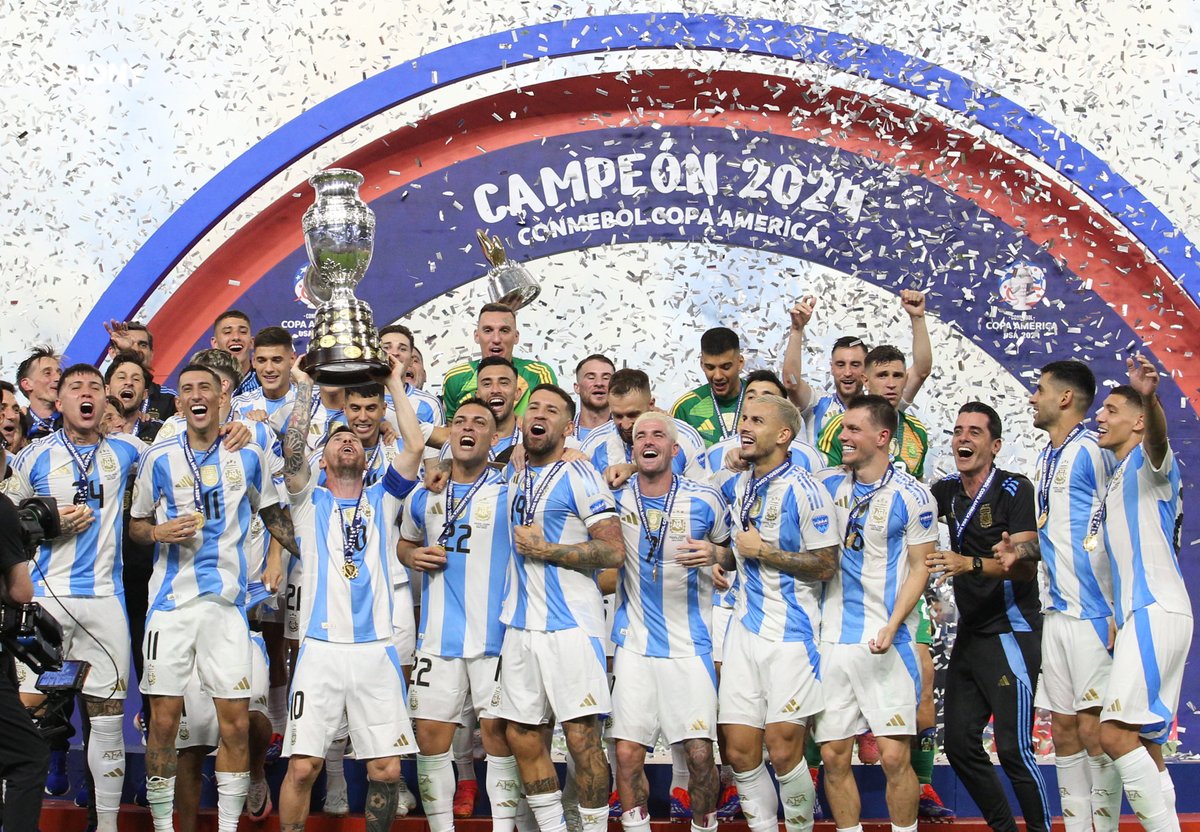 Jogadores da seleção argentina comemorando a vitória na Copa América 2024 com o troféu, em meio a confetes.