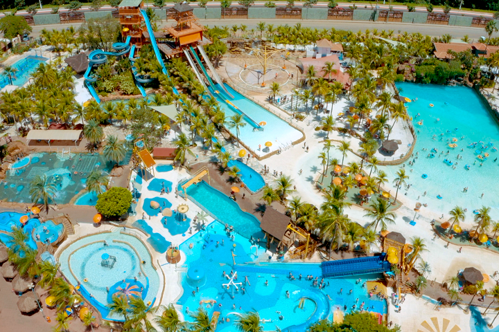 Visão aérea do parque aquático Thermas dos Laranjais em Olímpia, destacando as piscinas, toboáguas e áreas de lazer rodeadas por palmeiras.