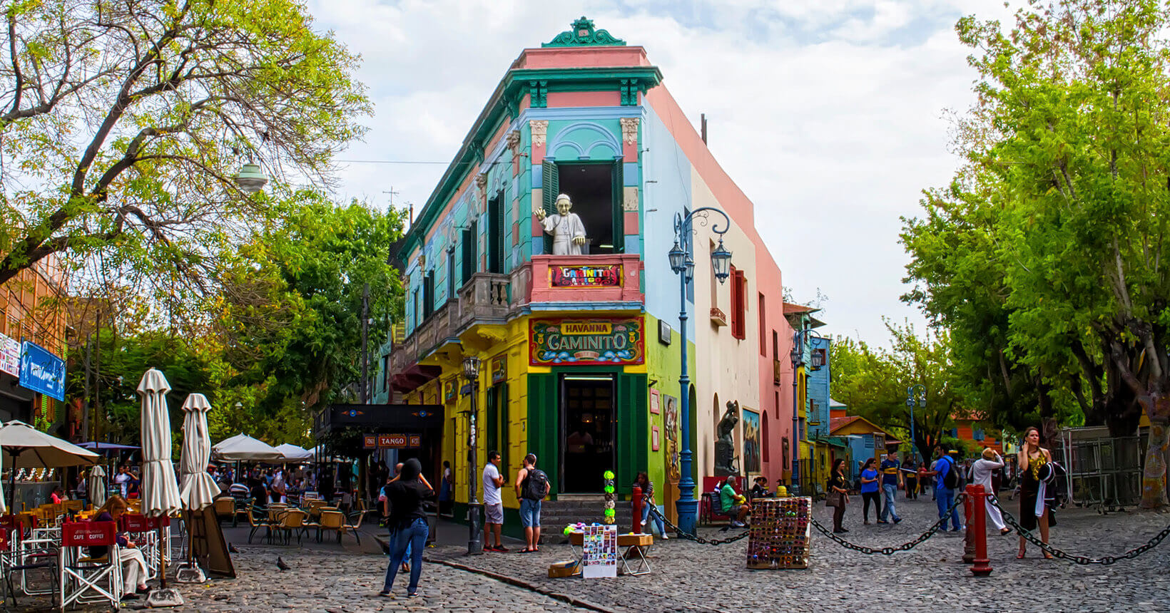 Rua colorida e movimentada no bairro Caminito, em Buenos Aires, Argentina, com arquitetura tradicional e pessoas explorando o local.