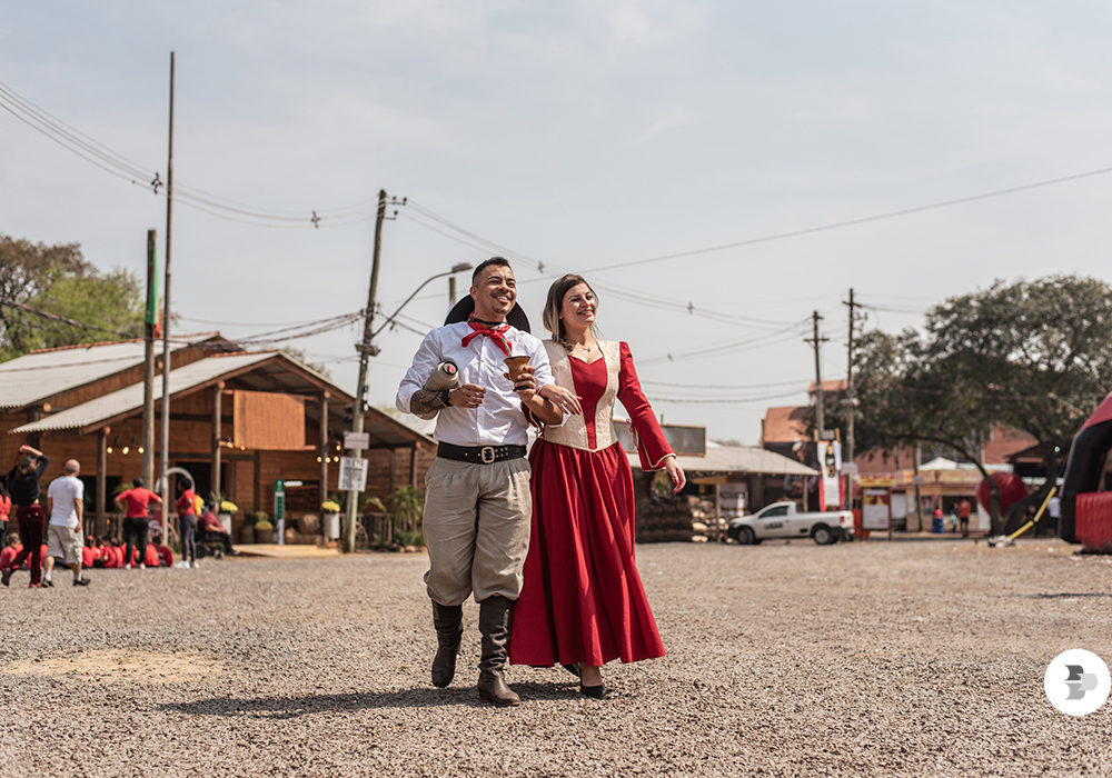 Casal em trajes típicos gaúchos em feira tradicional na Serra Gaúcha, simbolizando a retomada do turismo nacional no Rio Grande do Sul.