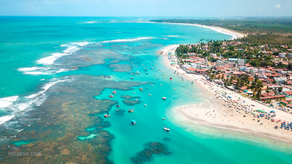 Vista aérea de uma praia paradisíaca no Nordeste brasileiro, destacando a beleza do litoral e o turismo intrarregional.