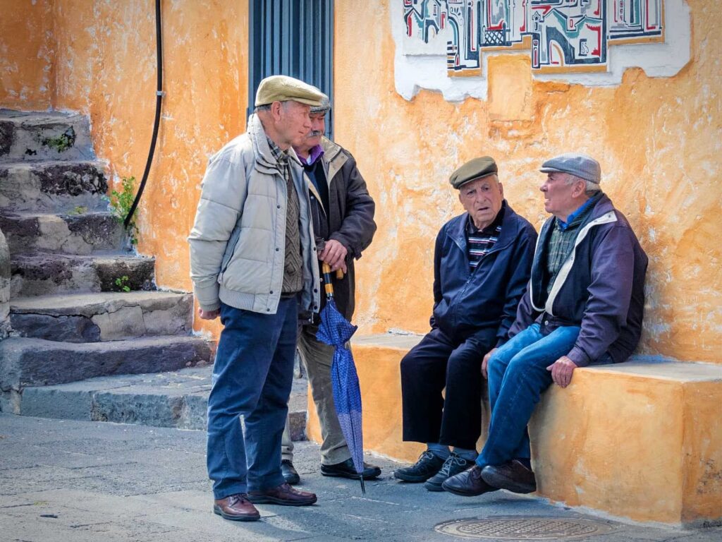 Grupo de idosos conversando em uma rua da Sardenha, simbolizando a longevidade na região.