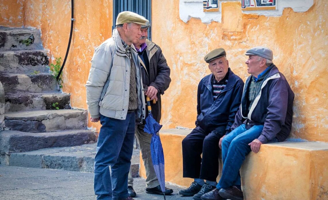 Grupo de idosos conversando em uma rua da Sardenha, simbolizando a longevidade na região.