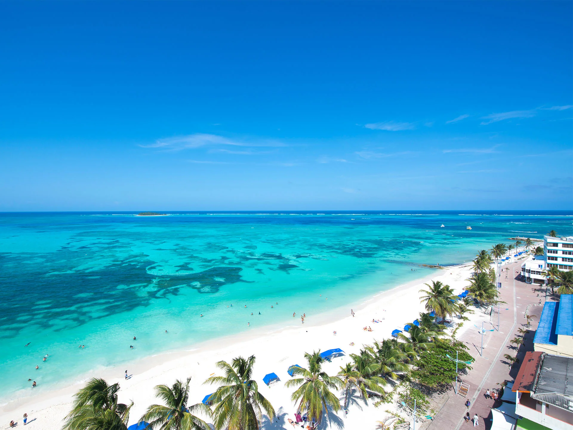 Praia de San Andrés com mar de águas cristalinas e coqueiros ao longo da orla.