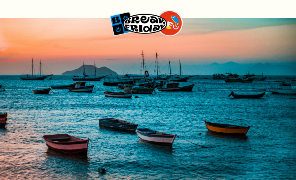 Barcos coloridos ancorados ao pôr do sol em Búzios, Rio de Janeiro, com montanhas ao fundo, representando a beleza natural da região de Arraial do Cabo e Búzios.