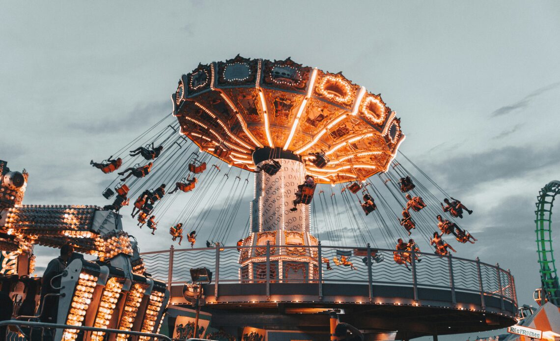 Brinquedo giratório iluminado em um parque de diversões, crianças aproveitando a experiência com alegria.