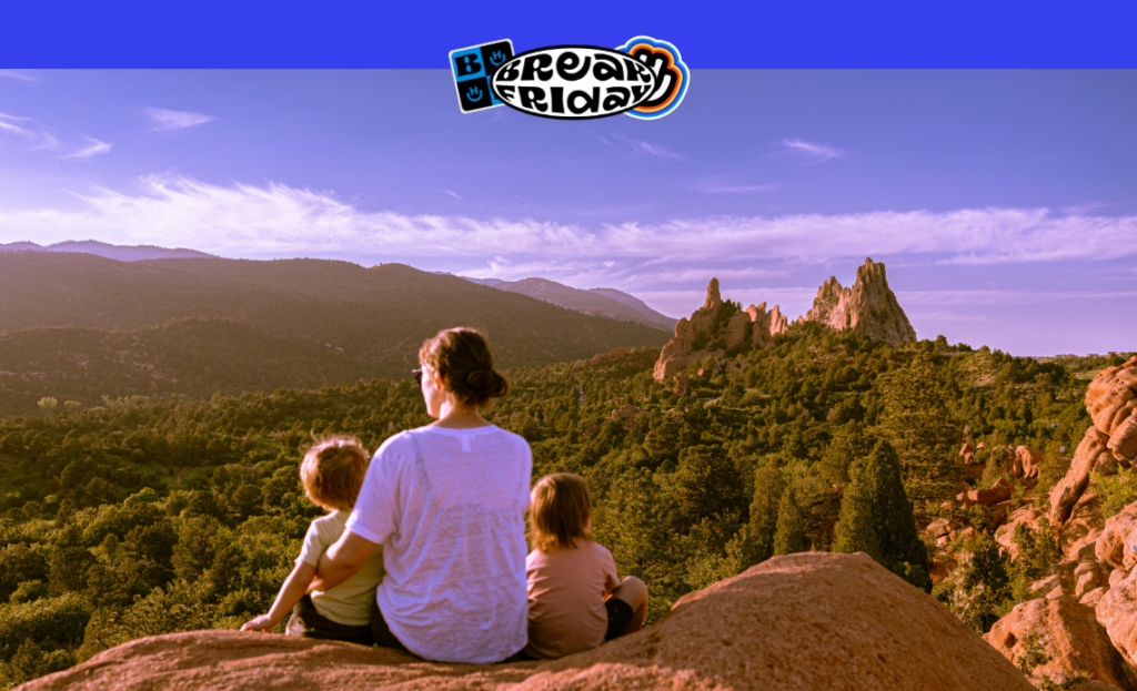 Mãe e dois filhos sentados em uma rocha, observando uma vista montanhosa ao pôr do sol durante uma viagem de ônibus em um feriado.