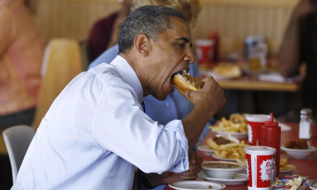 Ex-presidente Barack Obama apreciando um hot dog em um restaurante de fast food.