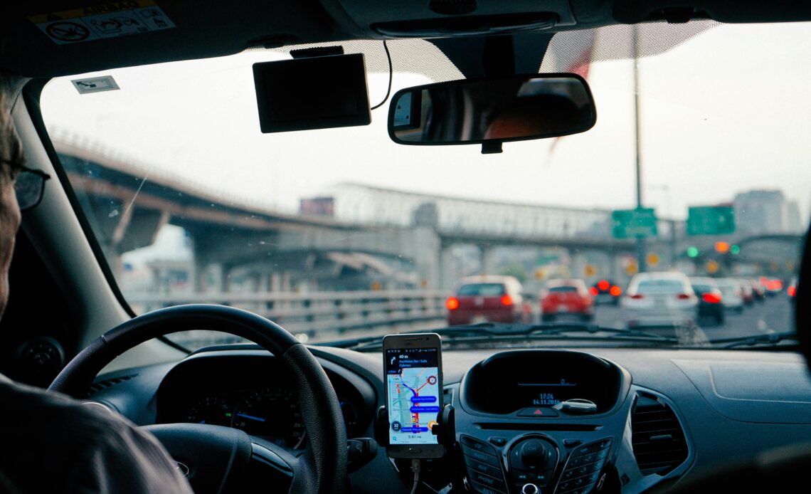 Motorista utiliza Google Maps com Inteligência Artificial enquanto dirige em uma estrada movimentada.