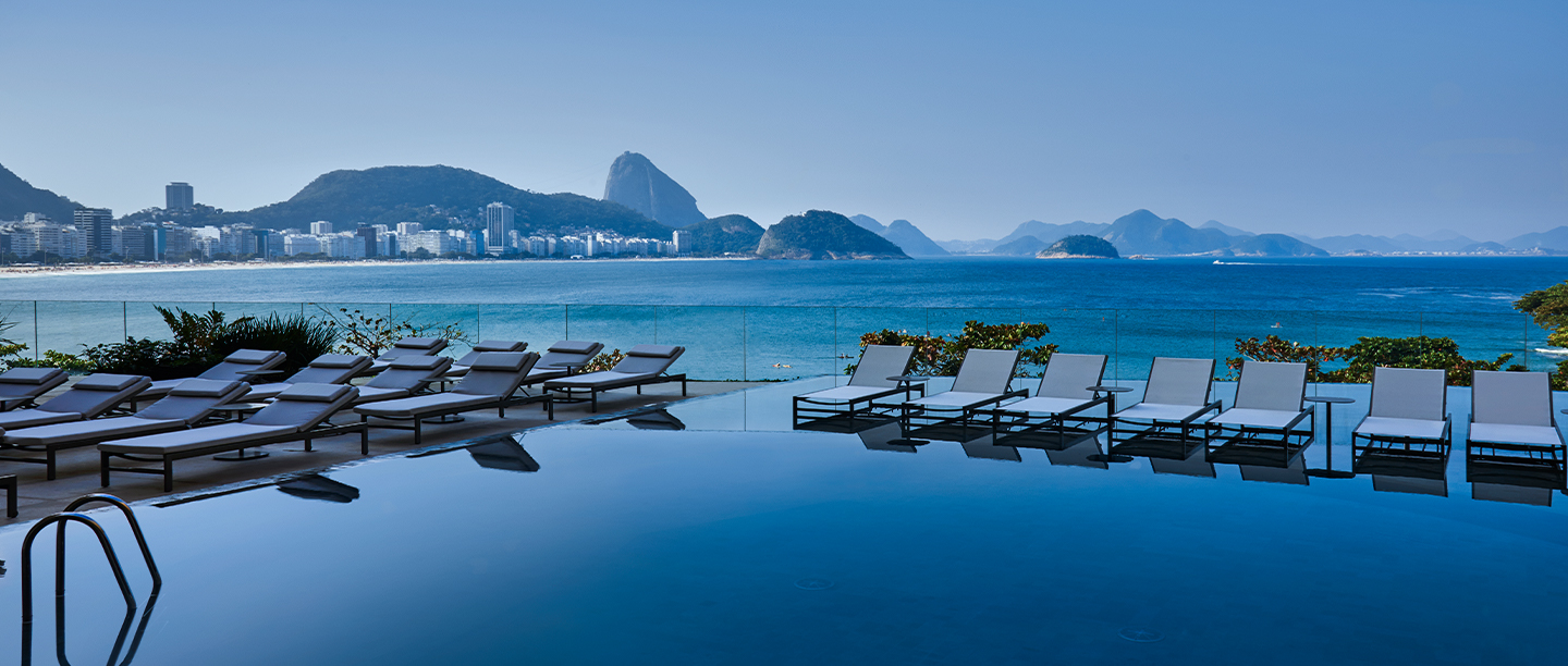 Vista deslumbrante da piscina infinita do Hotel Fairmont em Copacabana, com o Pão de Açúcar ao fundo.