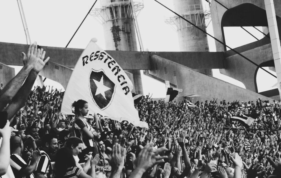 Torcida do Botafogo exibe bandeira com a palavra 'Resistência' durante jogo, em uma demonstração de apoio ao clube.