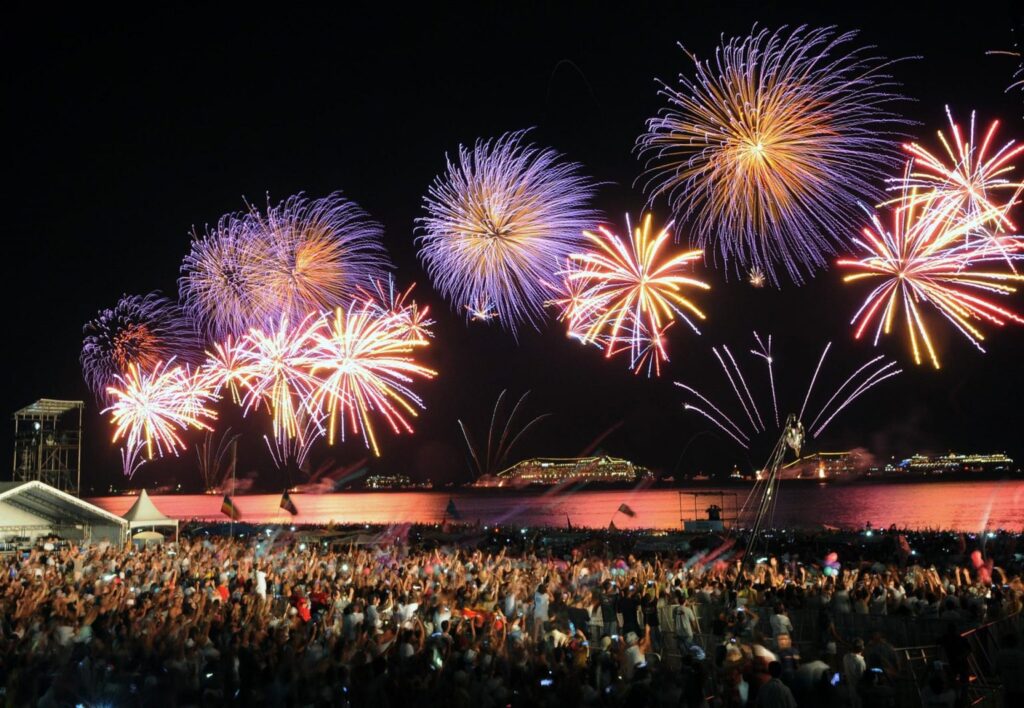 Imagem da queima de fogos de artifício no Réveillon, com vista para a praia e multidão celebrando a virada de Ano Novo em um dos melhores destinos de Réveillon do Brasil.