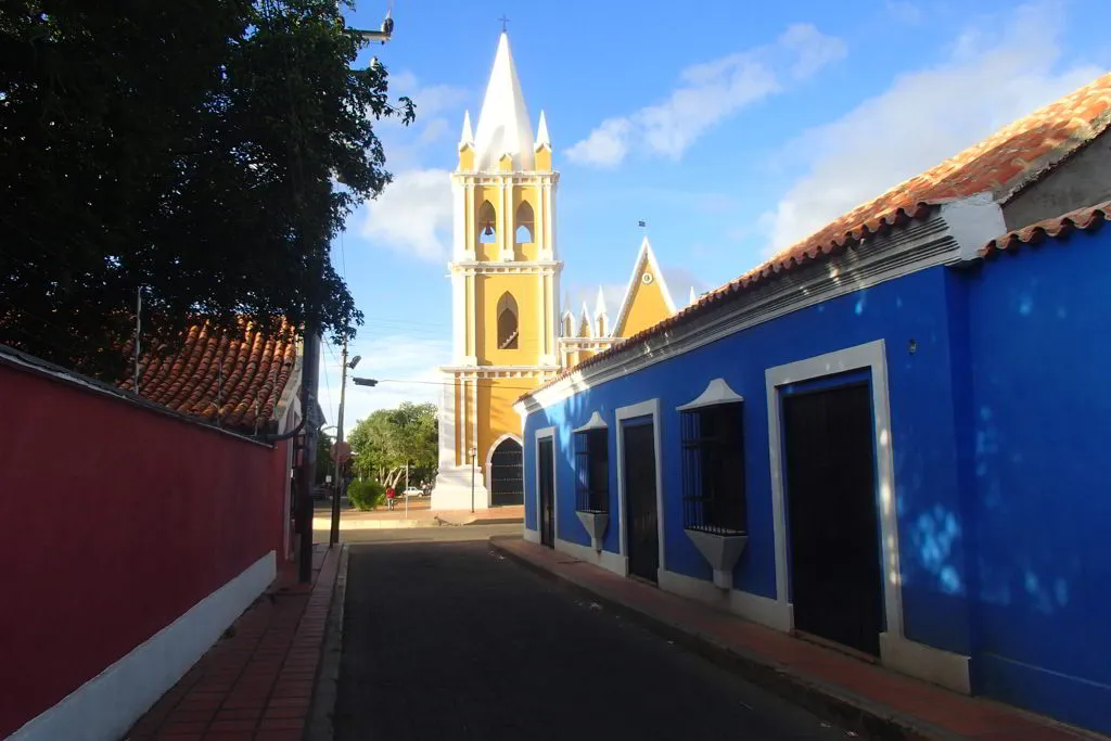 Rua histórica em Coro, na Venezuela, com vista para uma igreja, patrimônio mundial em risco de extinção reconhecido pela UNESCO.