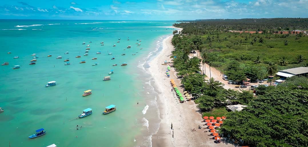 Vista aérea de São Miguel dos Milagres, Alagoas, com praias de águas cristalinas e jangadas típicas, destino ideal para o Réveillon 2025.