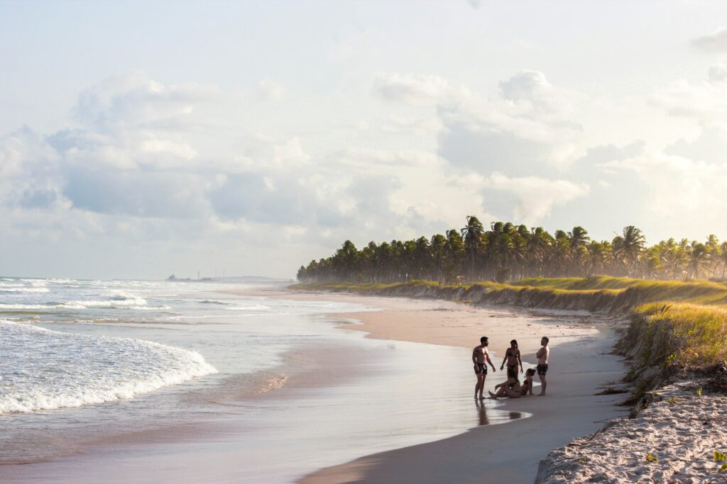 Praia deserta em Alagoas com grupo de amigos aproveitando a paisagem tropical, um dos destaques do Prêmio O Melhor de Viagem e Turismo 2024/2025.