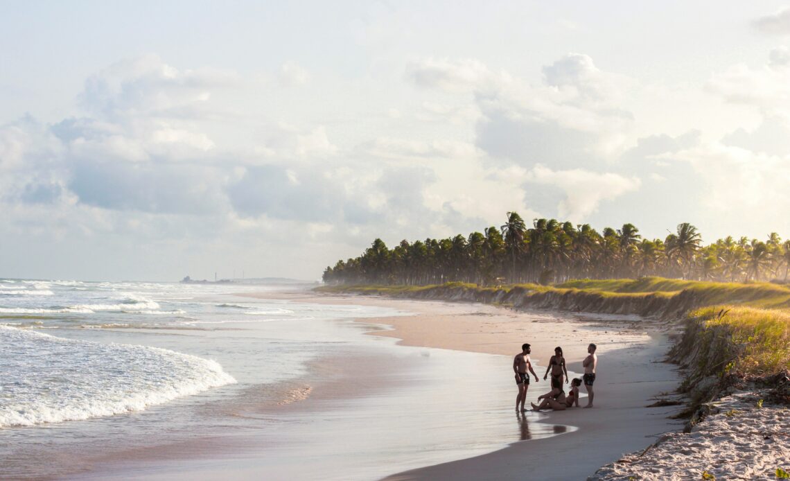 Praia deserta em Alagoas com grupo de amigos aproveitando a paisagem tropical, um dos destaques do Prêmio O Melhor de Viagem e Turismo 2024/2025.