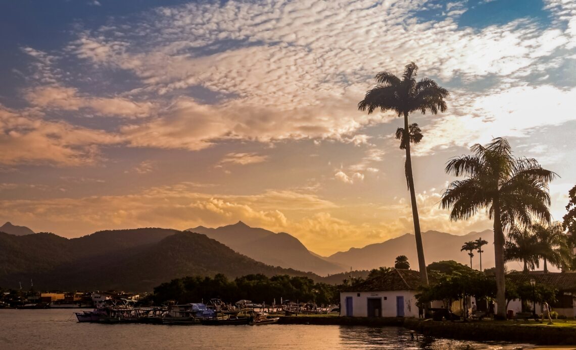 Vista de Paraty ao entardecer com montanhas ao fundo e barcos ancorados, ideal para pacotes rodoviários no Natal.