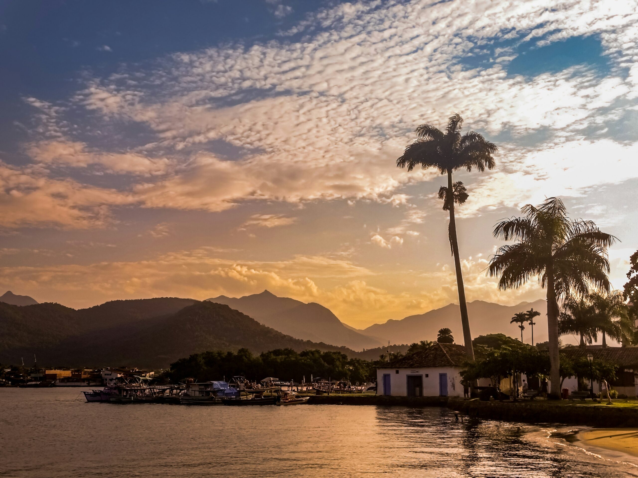 Vista de Paraty ao entardecer com montanhas ao fundo e barcos ancorados, ideal para pacotes rodoviários no Natal.