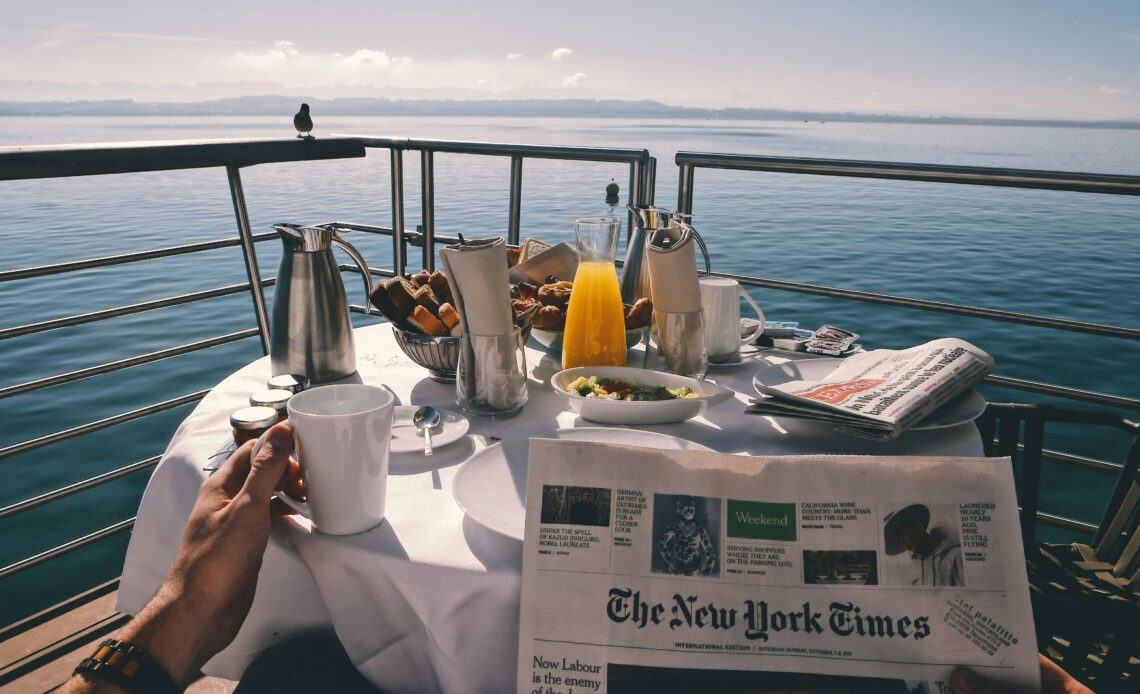 Mesa de café da manhã em um cruzeiro com vista para o mar, destacando a experiência relaxante e o impacto econômico dos cruzeiros.