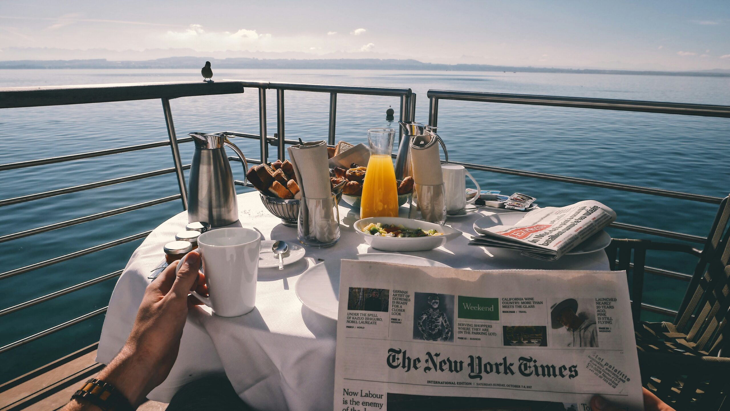 Mesa de café da manhã em um cruzeiro com vista para o mar, destacando a experiência relaxante e o impacto econômico dos cruzeiros.