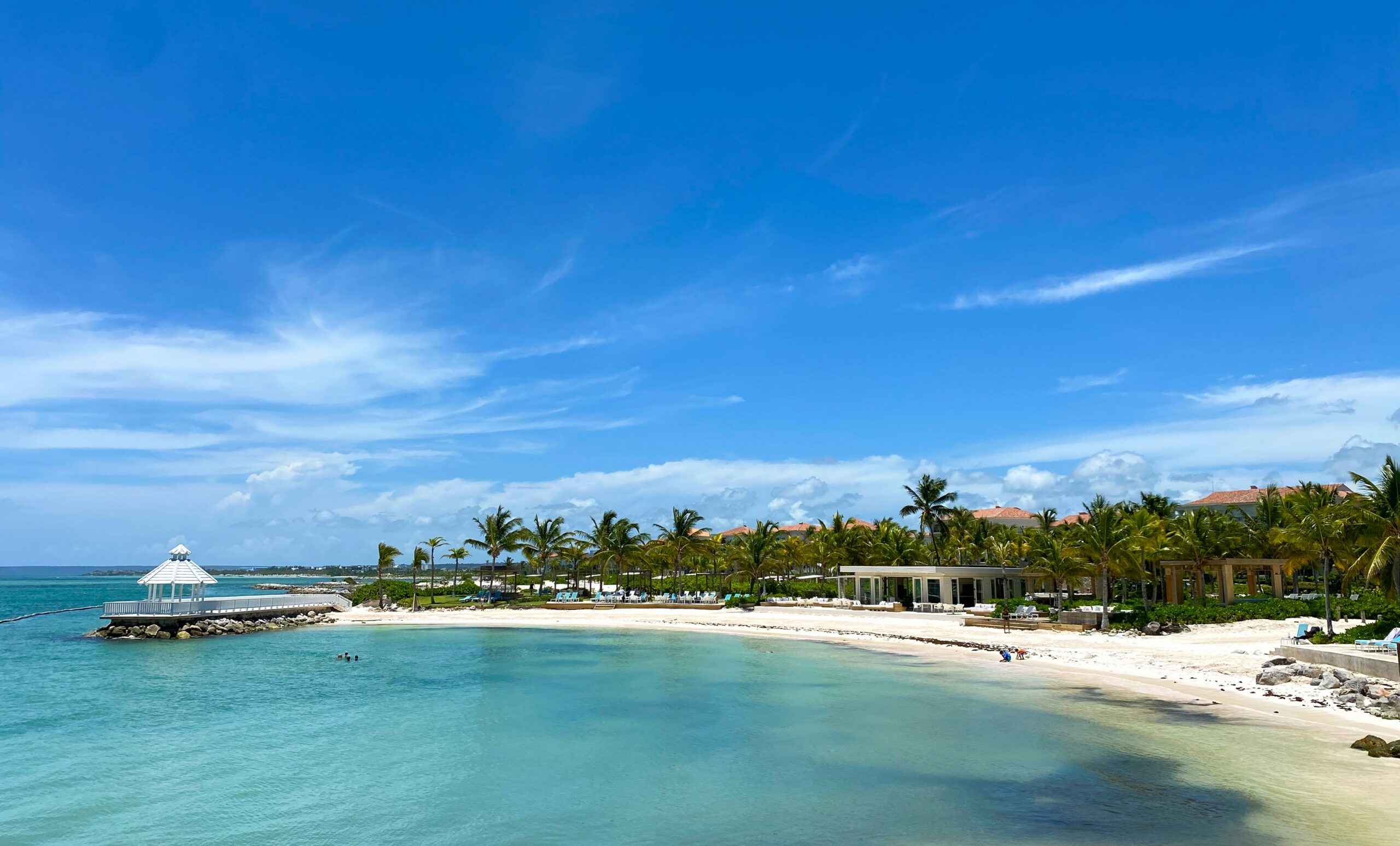 Vista paradisíaca de uma praia em Punta Cana, Caribe, com águas cristalinas e um resort all inclusive ao fundo.