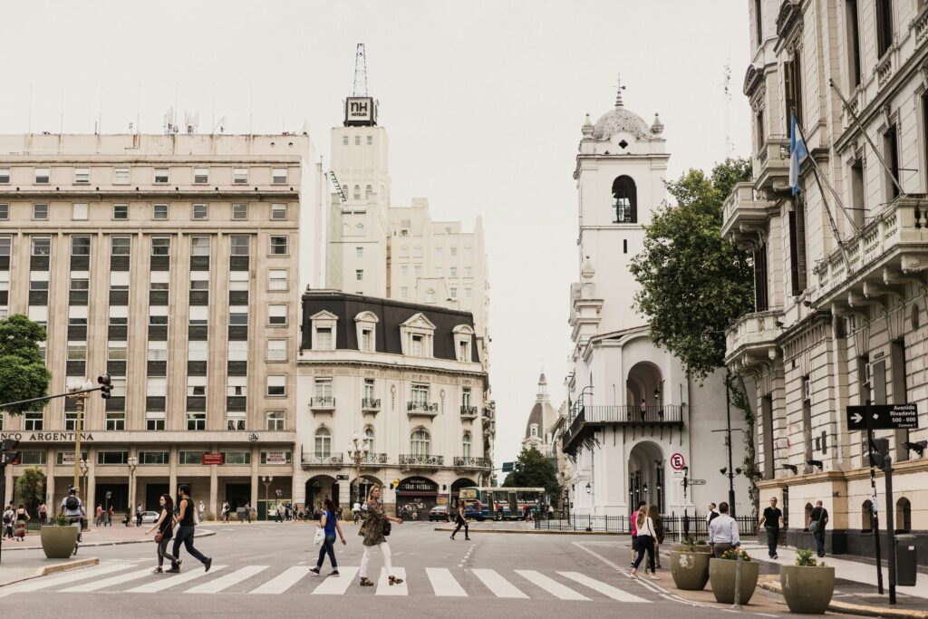 Cruzamento em Buenos Aires com arquitetura histórica e pedestres atravessando, refletindo o impacto econômico no turismo da Argentina.